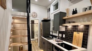 A modern kitchen with a central island, built-in appliances, and a wooden staircase.