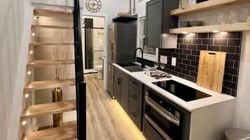 A modern kitchen with a central island, built-in appliances, and a wooden staircase.