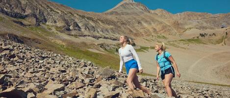 Two people hiking on rocky terrain with a mountain in the background.
