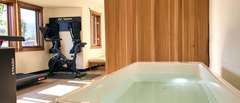 A room with a large bathtub, exercise equipment, and a window with a view.