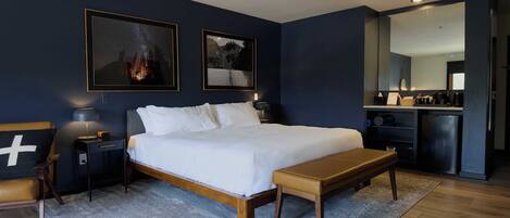 Un dormitorio con cama, mesitas de noche, un banco, mesilla y cómoda.