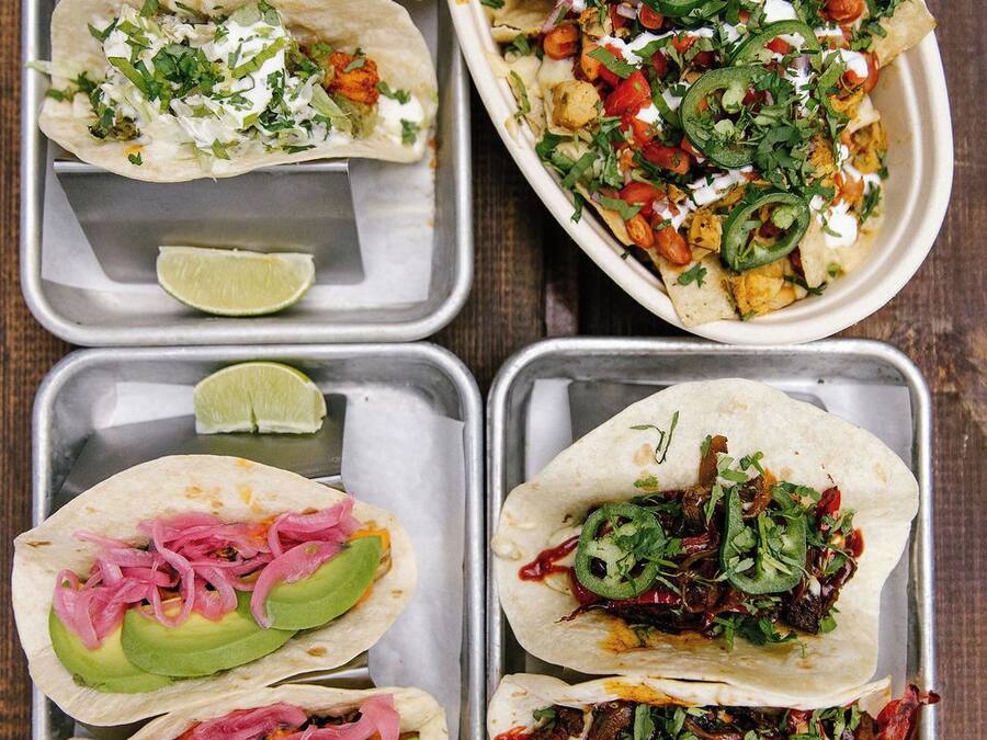 Un vassoio con quattro tipi diversi di tacos, ognuno guarnito in modo particolare.
