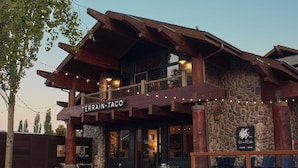 A restaurant with a stone facade, wooden beams, and outdoor seating. - Gravity Haus Big Sky (Big Sky)