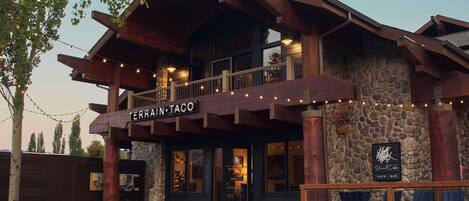 A restaurant with a stone facade and wooden beams, named 'TERRAIN TACO,' featuring outdoor seating and string lights.