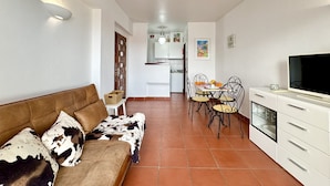 A living room with a brown sofa and a dining area with a table and chairs.