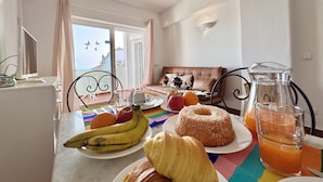 A dining area with a table set for breakfast, including fruits, a donut, and a glass of orange juice.