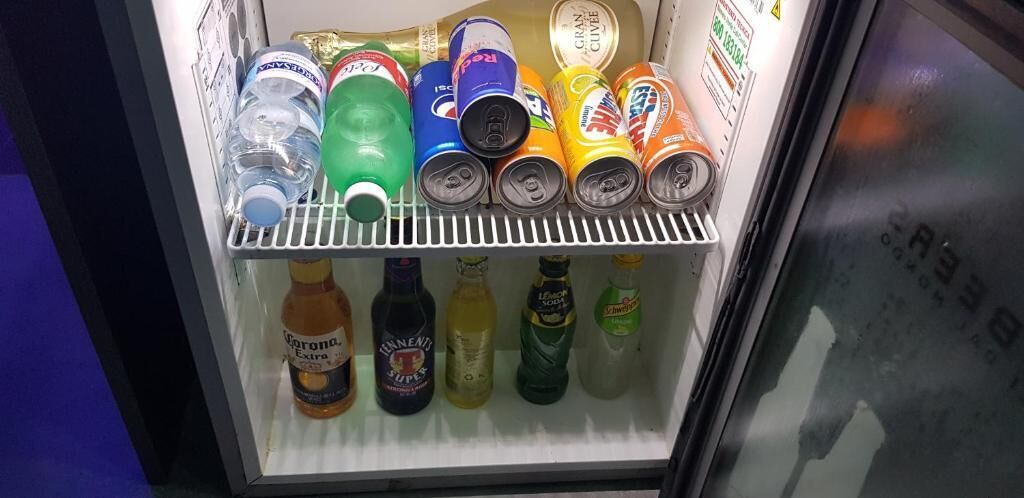 Een koelkast gevuld met verschillende drankjes, zoals frisdranken, water en alcoholische dranken.