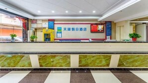 A hotel reception area with a marble counter, a reception desk, and a wall with a sign in Chinese. - Tianhu Hotel (Nanjing)
