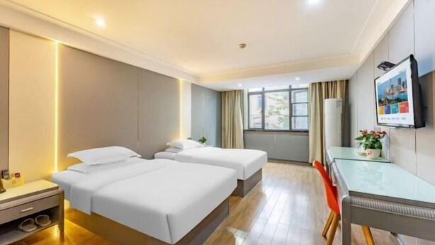 A hotel room with two beds, a desk, a chair, a TV, and a window with curtains. - Tianhu Hotel (Nanjing)