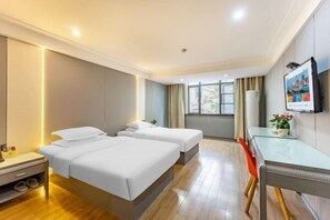 Una habitación de hotel con dos camas, un escritorio, una silla, un televisor y una ventana con cortinas.