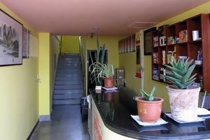 A reception area with a staircase, potted plants, and a bookshelf.