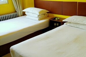 A hotel room with two single beds, a wooden headboard, a nightstand with a lamp, and a radiator. - Langting Business Hotel (Yantai)