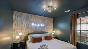 Een hotelkamer met een bed, een nachtkastje, een muur met een zebraprint, een plafondlamp en een raam met gordijnen.