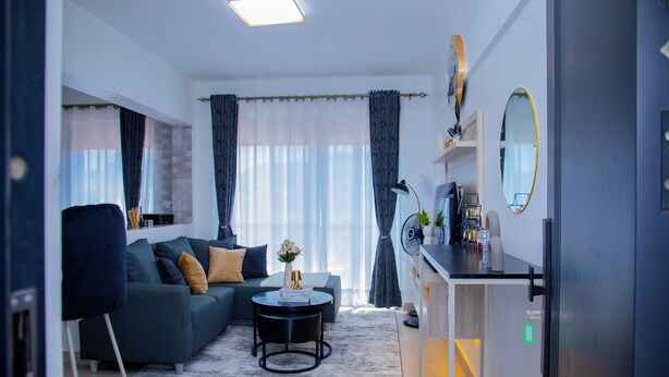 Una sala de estar moderna con sofá, mesa de centro y comedor con refrigerador.