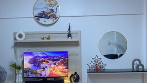 Una sala moderna con televisor de pantalla plana, chimenea empotrada, espejo redondo y comedor con mesa y sillas.