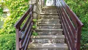 A stone staircase with wooden railings, surrounded by greenery. - Hollies Cottage (Truro)