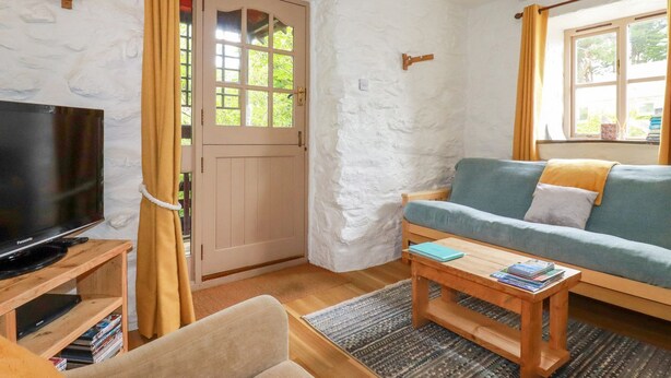 A cozy living room with a television, sofa, and coffee table. - Hollies Cottage (Truro)