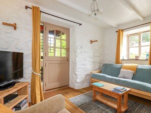 Ein gemütliches Wohnzimmer mit Fernseher, Sofa und Couchtisch.