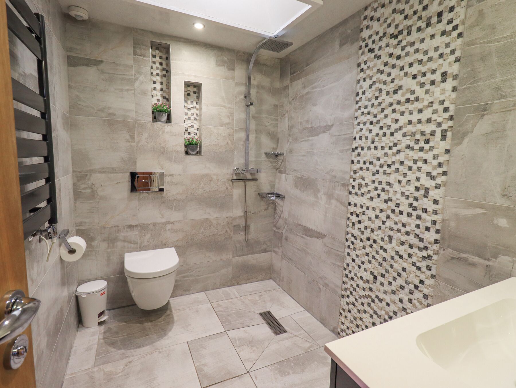 A modern bathroom with a shower, toilet, and sink.