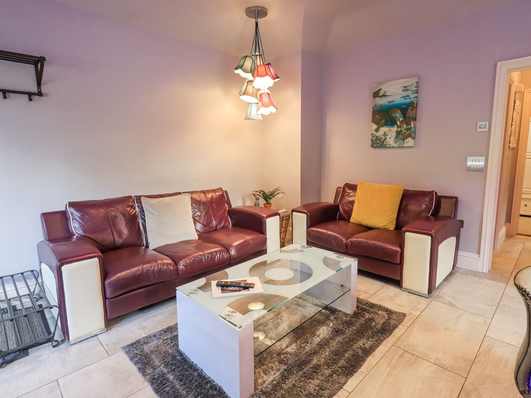 Ein Wohnzimmer mit zwei Ledersofas, einem Glastisch und einer Pendelleuchte.