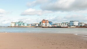 A beach with a row of colorful buildings in the background. - Rolles Rainbow (Exmouth)
