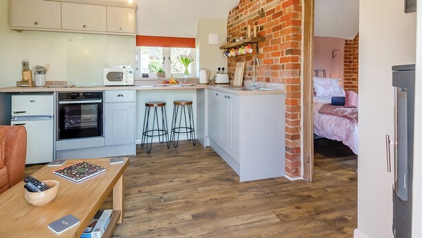 A compact kitchen with a microwave, oven, and stools. - Beautiful romantic converted barn located in a quiet setting. (Wingfield, near Diss)