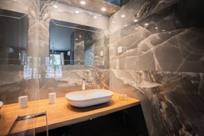 A modern bathroom with a large marble sink, a wooden countertop, and a mirror.