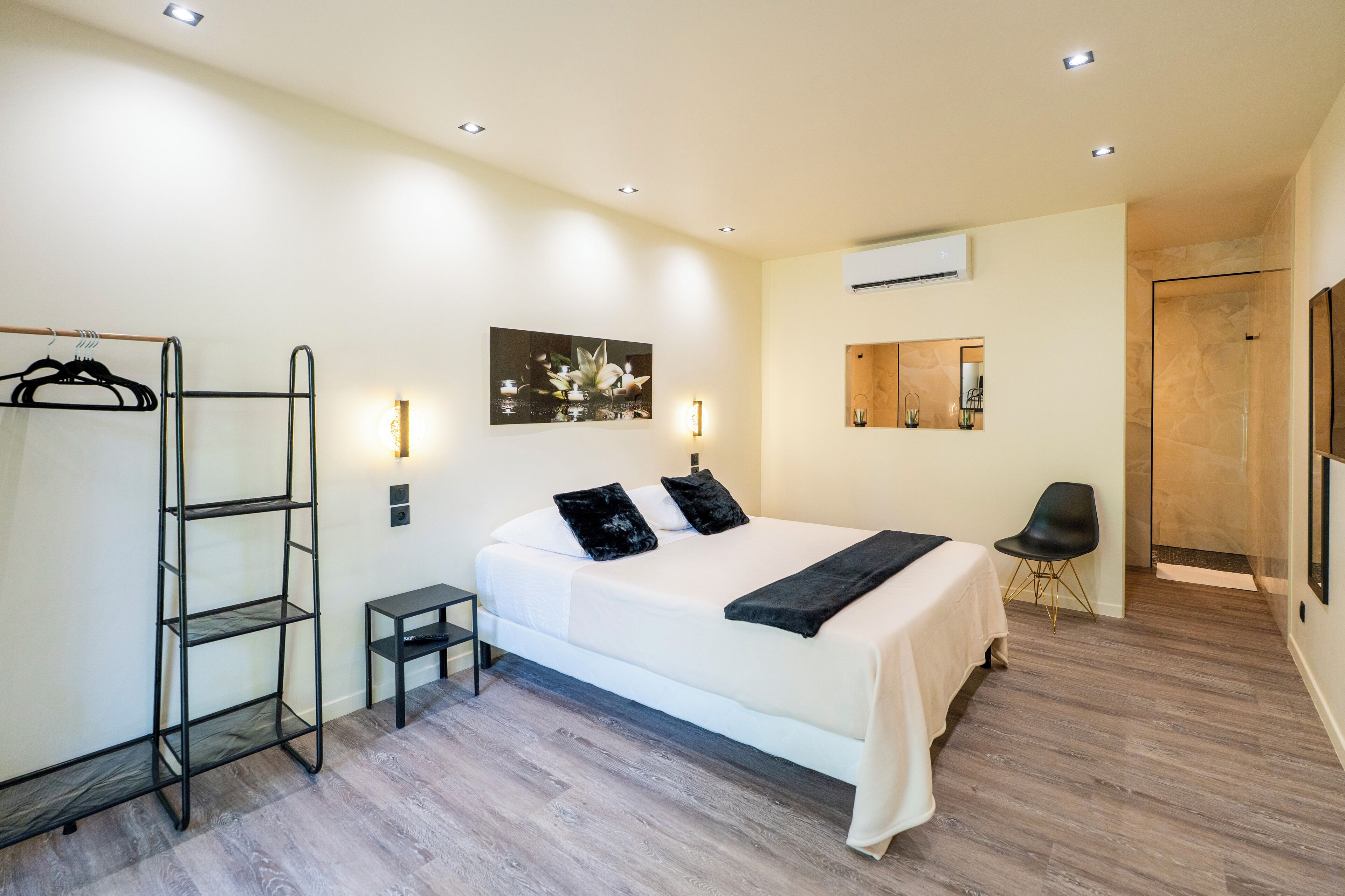 Une chambre à coucher avec un lit, une armoire, une petite table, une chaise et un tableau accroché au mur.