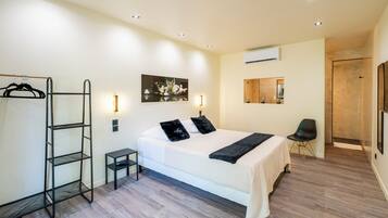 Une chambre à coucher avec un lit, une armoire, une petite table, une chaise et un tableau accroché au mur.