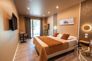 A modern hotel room with a large bed, a desk, and a glass table.