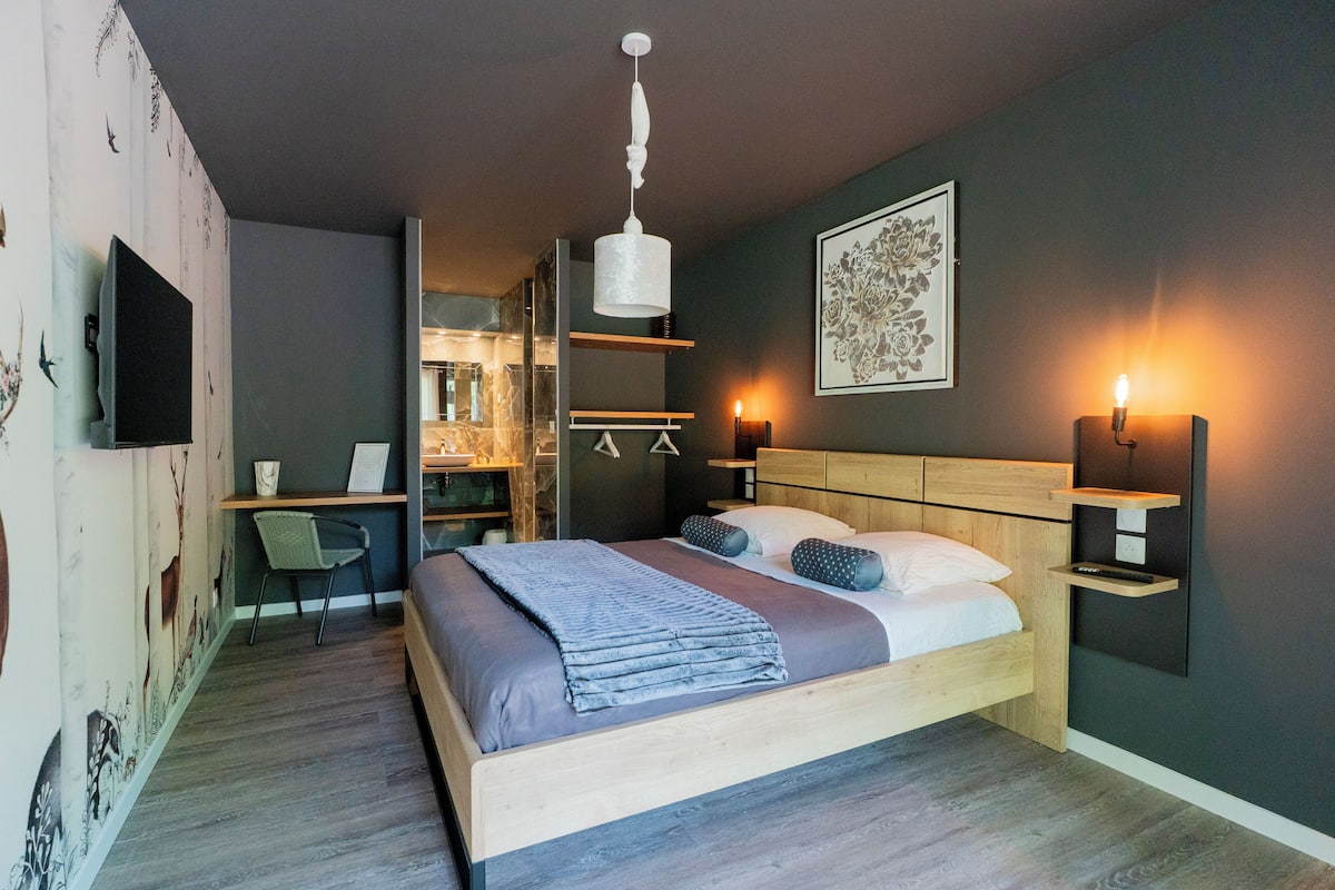 A modern bedroom with a wooden bed, bedside tables, a desk, and a chair.