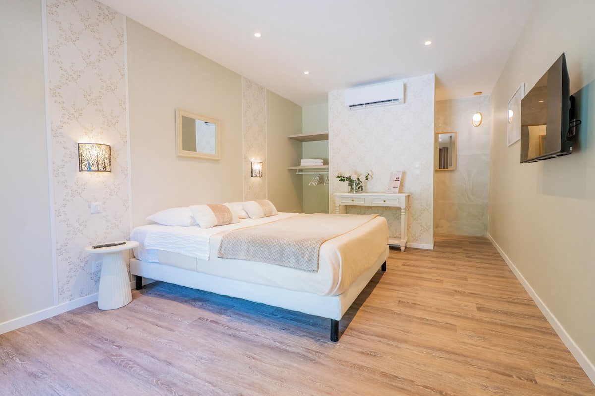 A modern bedroom with a large bed, bedside tables, a desk, and a mirror.