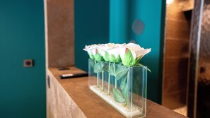A row of clear glass vases with artificial flowers on a wooden surface.