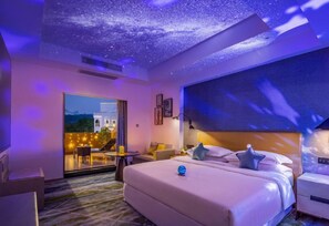 A hotel room with a large bed, a desk, a chair, and a view of the outside. - Sheraton Guilin Hotel (Guilin)