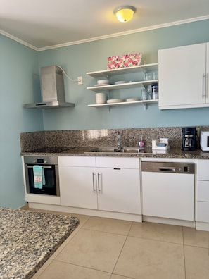 A kitchen with a stove, oven, dishwasher, microwave, and granite countertop.