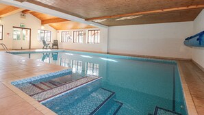 An indoor swimming pool with tiled flooring and wooden ceiling beams. - Beaver Cottage (Thirsk)