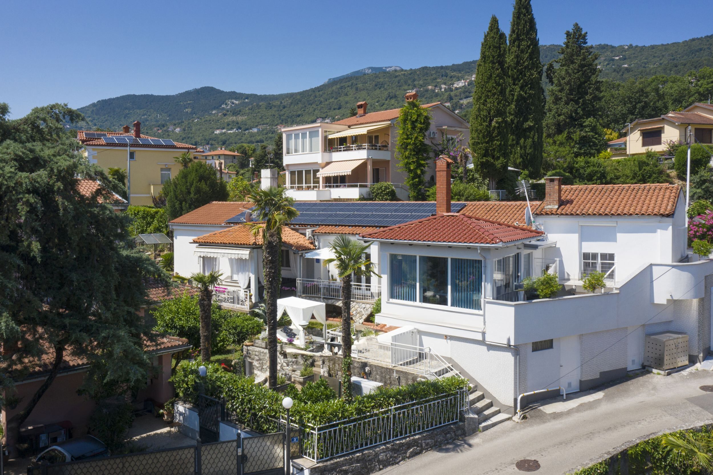 A residential building with a modern design, featuring a balcony, solar panels, and a view of the surrounding landscape.