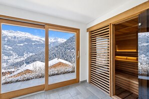 Una habitación con amplios ventanales correderos que dan a montañas nevadas.