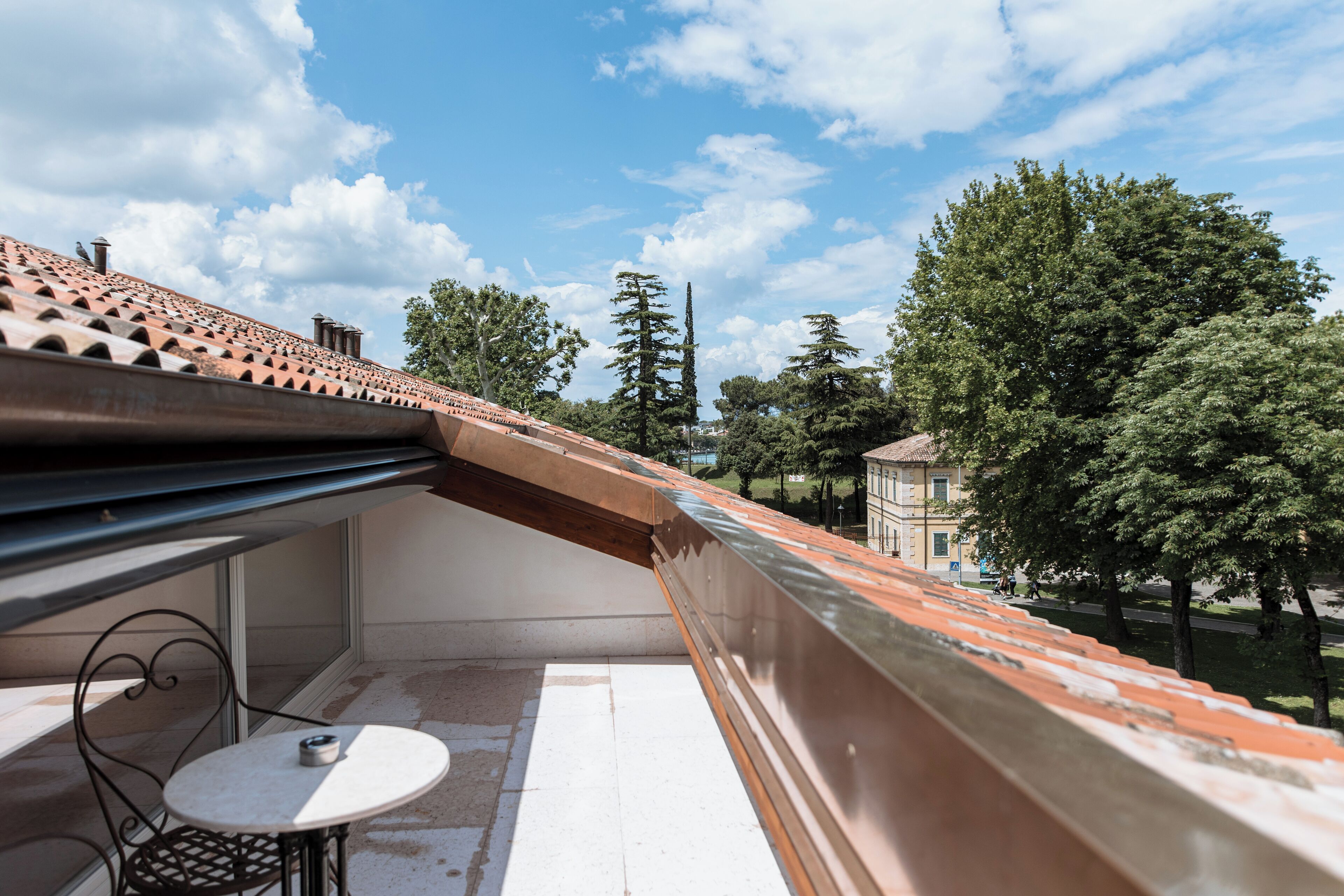 A balcony with a tiled roof, a small round table, and a chair.