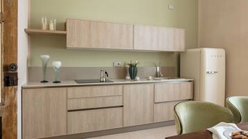 A modern kitchen with light wood cabinets, a stainless steel sink, and a white refrigerator.