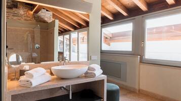 A modern bathroom with a large sink, mirror, and wooden ceiling beams.