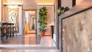A hallway with a potted plant, a dining area with chairs, and a large abstract painting on the wall. - Pavillon Suite (Peschiera del Garda)