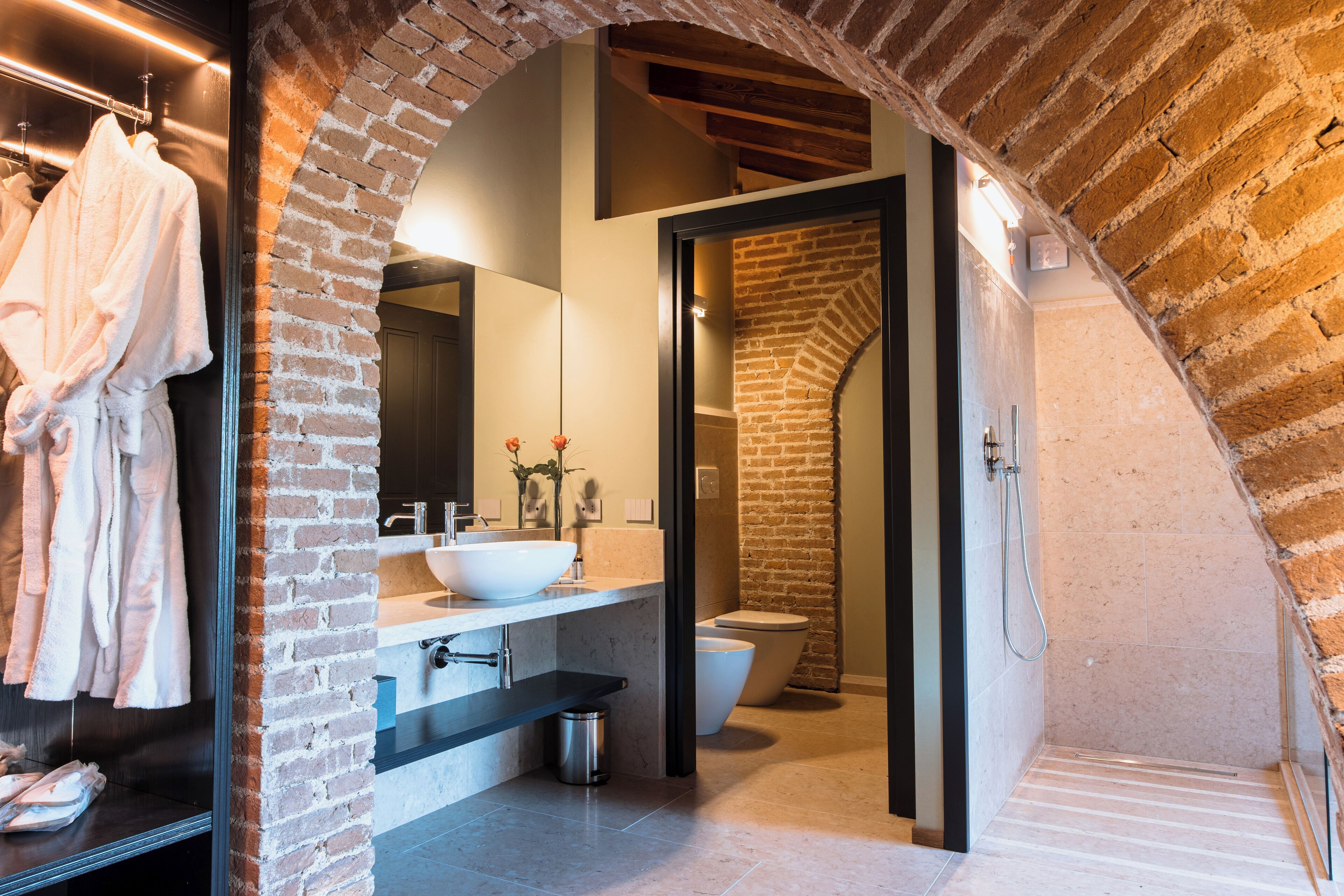 A modern bathroom with a brick archway, a white sink, and a toilet.