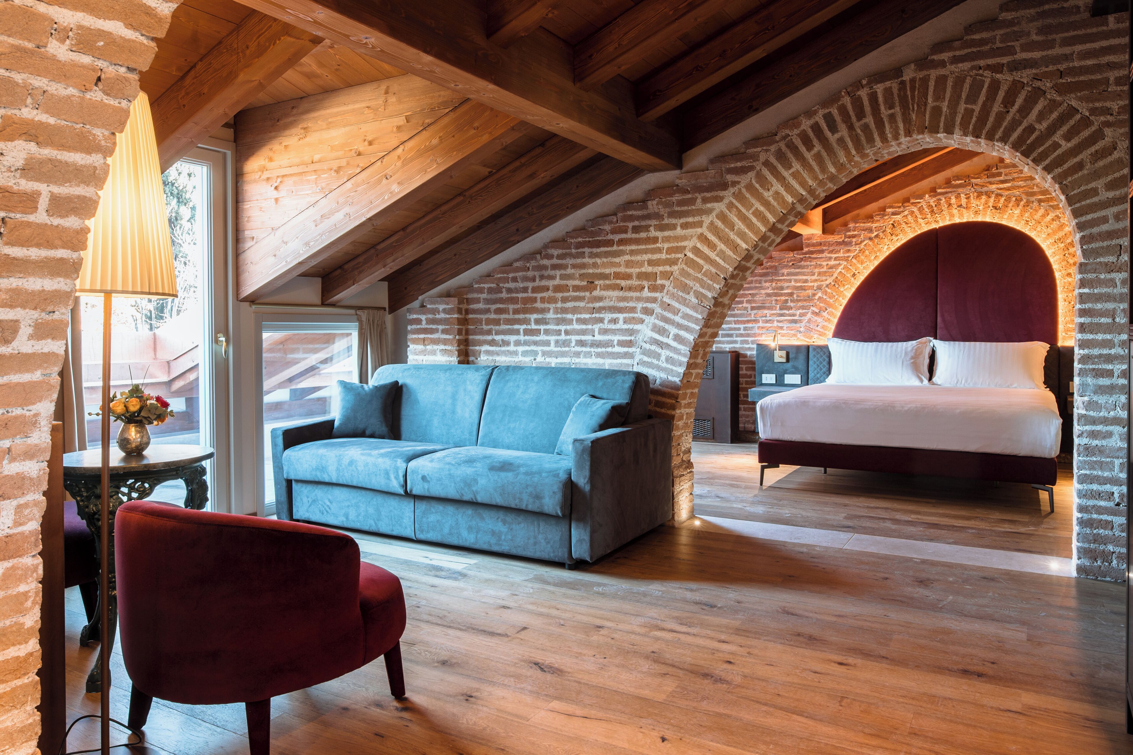 A room with a loft bed, a sofa, and a red chair.