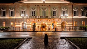 A grand building with a central entrance, arched windows, and a clock above the main door. - Pavillon Suite (Peschiera del Garda)