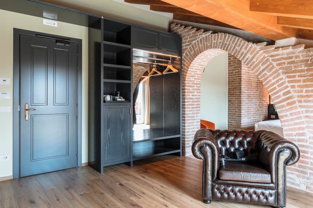 Quarto com armário, poltrona de couro e arco de tijolos.