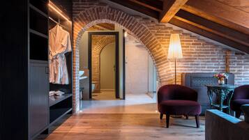 A room with a wooden floor, a brick archway, a hanging robe, a lamp, and two chairs.