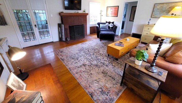 A living room with a fireplace, sofa, coffee table, and a TV mounted on the wall. - Private cottage close to SoFi, FiFa fans welcome! (Long Beach)