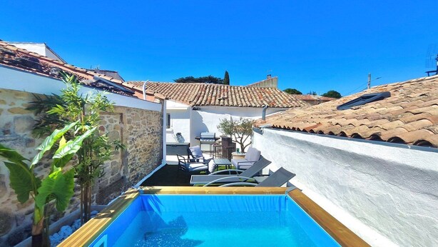 A swimming pool with a stone wall on one side and a tiled roof on the other.