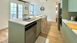 A modern kitchen with a central island, built-in dishwasher, and a view to a balcony.